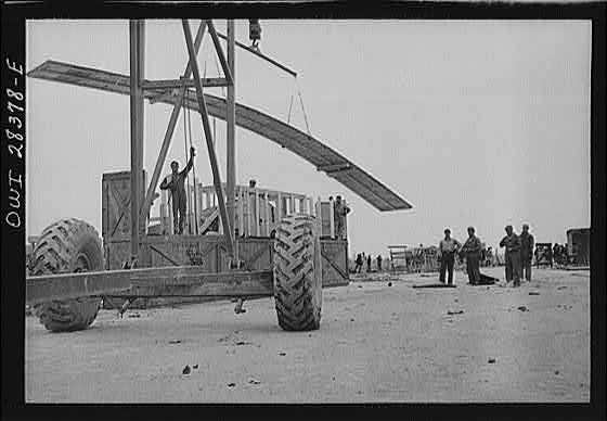 A derrick moving a chassis as the men work ankle deep in water at an American truck assembly plant somewhere in Iran.