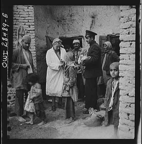 Teheran, Iran. Mrs. Louis Dreyfus, wife of the United States Minister to Iran, giving food to native children