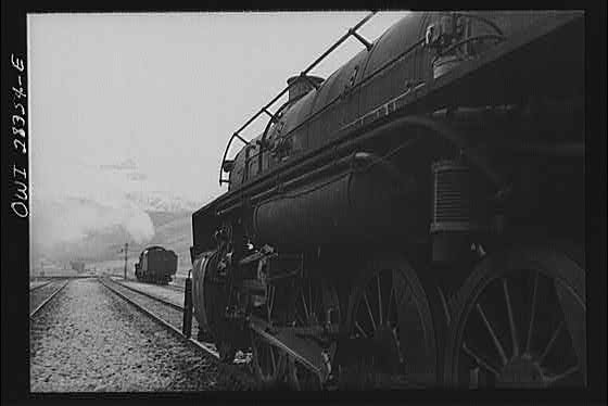 An American engine pulling a great load of supplies for Russia along a mountain- rimmed plateau somewhere in Iran.